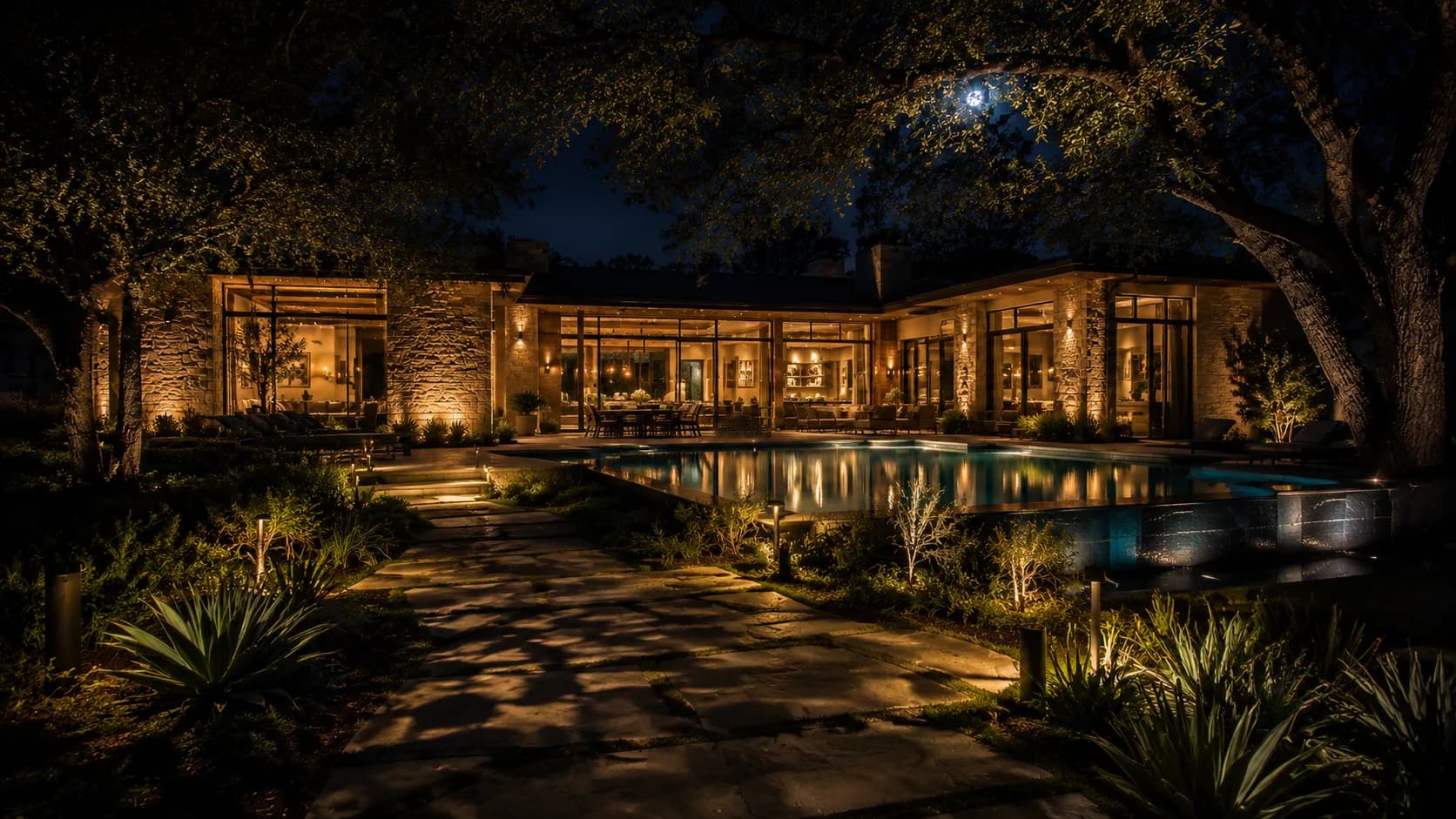 Texas estate backyard at night — path lighting, moonlit oaks, glowing pool